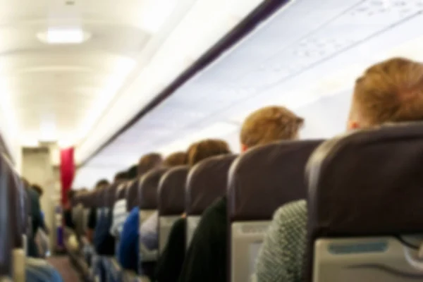 Blur background of passenger plane cabin with people sitting in armchairs, Plane travel concept