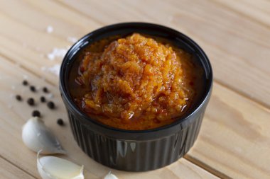 Homemade adjika sauce in a bowl close-up, on a wooden table