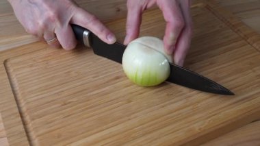 Mutfak tahtasında soğan doğrayan bir kadın, yakın plan.