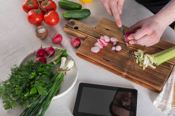 The guy prepares a vegetable salad from raw foods, diet