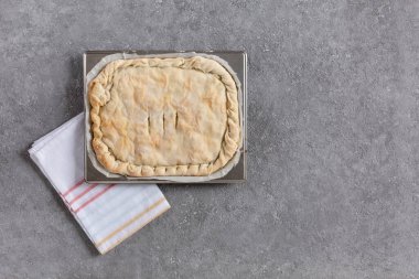 Homemade pie with meat or vegetable filling on a metal tray, copy space, top view, homemade pastries