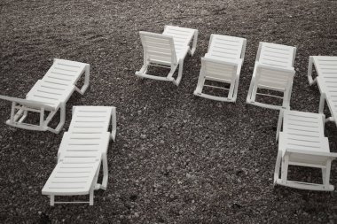 Kayalık bir sahil kıyısında boş plaj sandalyeleri.