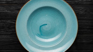 Siyah ahşap masada boş mavi tabak, üst manzara, yemek konsepti.