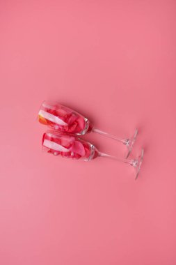 Sevgililer Günü arkaplanı, pembe arka planda gül yapraklarıyla dolu şampanya bardakları.