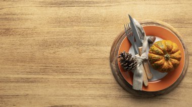 Çatal bıçaklı bir tabak Şükran Günü için süslenir. Balkabakları ve sonbahar ürünleri ahşap bir masada, üst görünümde.