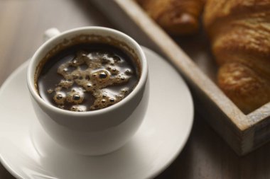Taze kruvasan ve bir fincan espresso, ahşap masa, işteyken atıştırma, dışarıda yemek.