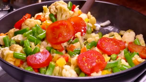 用冷冻切碎的蔬菜烹调蔬菜炖菜 西红柿 芦笋和卷心菜在锅里蒸着 用厨房的铲把菜搅拌一下 — 图库视频影像