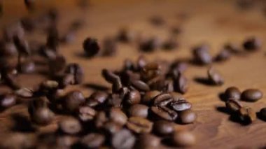 Ahşap zemine düşen kavrulmuş kahve çekirdekleri, yakın plan. Kahve çekirdeği, kahve arkaplanı. Kahverengi kahve çekirdeği dokusu.