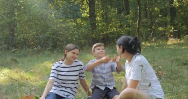 Mutlu bir aile doğada dinlenir. Köpek ve çocuklarla birlikte orman parkına yürü. Sıcak bir sonbahar gününde çimlerin üzerinde oturmak. 