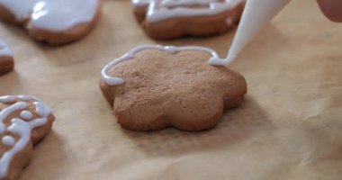 Zencefilli kurabiyeler kadın eliyle beyaz kremayla süslenir. Yılbaşı kurabiyeleri.