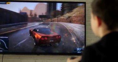 Evde joystick ile araba yarışı yapan bir çocuğun arka görüntüsü. Oyuncu ve bilgisayar oyunları