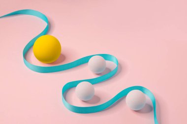 Abstract pastel tone coloured geometric shapes spheres and curved line on pink background. Still life image.