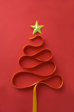 Kırmızı arkaplanda kurdele ile soyut Noel ağacı biçimi.