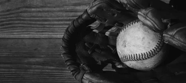Old rough baseball ball in black ball glove closeup for sport.