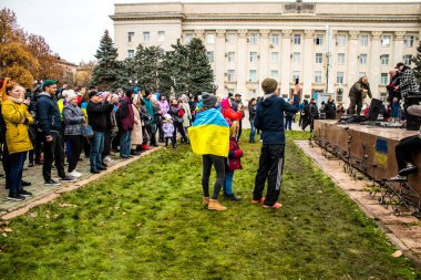 Ukrayna bayrağını pelerin şeklinde giyen bazı Kherson vatandaşları şehrin şehir merkezindeki Özgürlük Meydanı 'nda özgürlüğünü kutluyorlar. Rus birlikleri dokuz aylık bir işgal ve Ukraynalı bir karşı taarruz sonrasında Kherson 'dan ayrıldı.