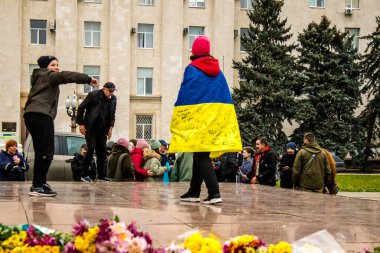 Ukrayna bayrağını pelerin şeklinde giyen bazı Kherson vatandaşları şehrin şehir merkezindeki Özgürlük Meydanı 'nda özgürlüğünü kutluyorlar. Rus birlikleri dokuz aylık bir işgal ve Ukraynalı bir karşı taarruz sonrasında Kherson 'dan ayrıldı.