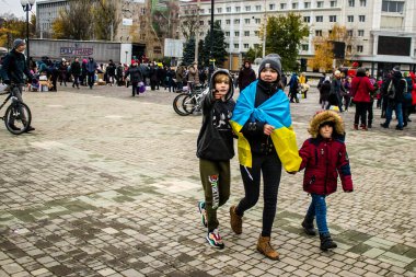 Ukrayna bayrağını pelerin şeklinde giyen bazı Kherson vatandaşları şehrin şehir merkezindeki Özgürlük Meydanı 'nda özgürlüğünü kutluyorlar. Rus birlikleri dokuz aylık bir işgal ve Ukraynalı bir karşı taarruz sonrasında Kherson 'dan ayrıldı.