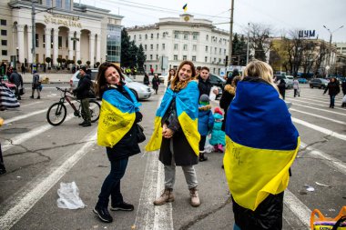 Ukrayna bayrağını pelerin şeklinde giyen bazı Kherson vatandaşları şehrin şehir merkezindeki Özgürlük Meydanı 'nda özgürlüğünü kutluyorlar. Rus birlikleri dokuz aylık bir işgal ve Ukraynalı bir karşı taarruz sonrasında Kherson 'dan ayrıldı.