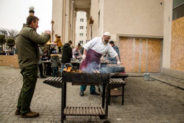 Kherson Meydanı 'nda bir lokantacı sokak mutfağı açıyor. Elektrik ve su olmamasına rağmen odun ateşiyle et pişiriyor. İnsanlar hayatlarını normal bir şekilde sürdürmek için örgütleniyorlar.