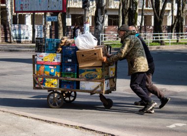 Bir bahçıvan sebzelerini Kherson 'da bir sokak köşesinde satıyor. Sabahın sonunda, güvenlik nedenlerinden dolayı Rus bombardıman alarmı yüzünden market bahçıvanı faaliyetlerini durdurur ve satılmamış sebzeleri alır. İşine devam edecek.