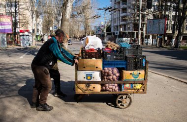 Bir bahçıvan sebzelerini Kherson 'da bir sokak köşesinde satıyor. Sabahın sonunda, güvenlik nedenlerinden dolayı Rus bombardıman alarmı yüzünden market bahçıvanı faaliyetlerini durdurur ve satılmamış sebzeleri alır. İşine devam edecek.