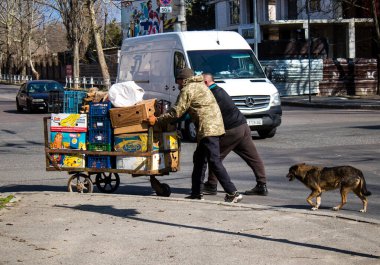 Bir bahçıvan sebzelerini Kherson 'da bir sokak köşesinde satıyor. Sabahın sonunda, güvenlik nedenlerinden dolayı Rus bombardıman alarmı yüzünden market bahçıvanı faaliyetlerini durdurur ve satılmamış sebzeleri alır. İşine devam edecek.