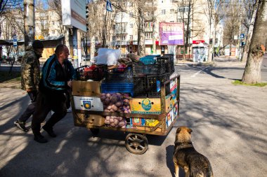 Bir bahçıvan sebzelerini Kherson 'da bir sokak köşesinde satıyor. Sabahın sonunda, güvenlik nedenlerinden dolayı Rus bombardıman alarmı yüzünden market bahçıvanı faaliyetlerini durdurur ve satılmamış sebzeleri alır. İşine devam edecek.