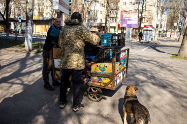 Bir bahçıvan sebzelerini Kherson 'da bir sokak köşesinde satıyor. Sabahın sonunda, güvenlik nedenlerinden dolayı Rus bombardıman alarmı yüzünden market bahçıvanı faaliyetlerini durdurur ve satılmamış sebzeleri alır. İşine devam edecek.