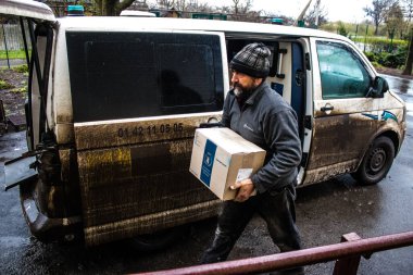 İnsanlar ambulanstan kutular dolusu erzak indiriyor.