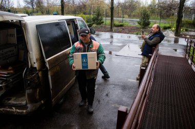 İnsanlar ambulanstan kutular dolusu erzak indiriyor.