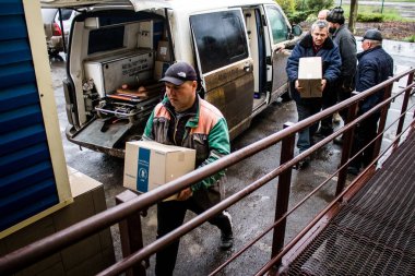İnsanlar ambulanstan kutular dolusu erzak indiriyor.