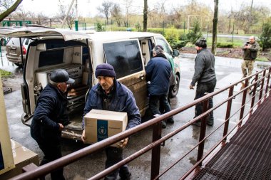 İnsanlar ambulanstan kutular dolusu erzak indiriyor.