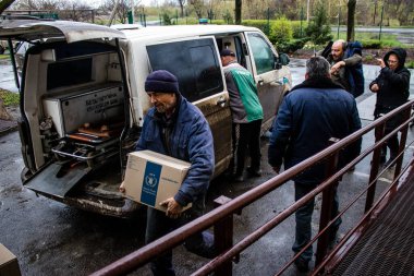 İnsanlar ambulanstan kutular dolusu erzak indiriyor.
