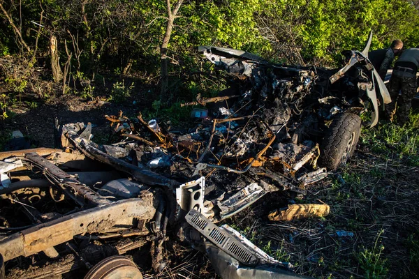 Stock image Ukrainian soldiers loading a car damaged by artillery fire in the combat zone near Bakhmut on the edge of a forest. The servicemen intend to salvage the engine of the vehicle so that it can be used again.