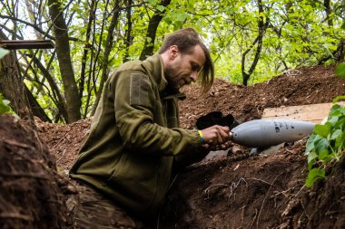 28. Topçu Taburu 'nun Ukraynalı askeri Bakhmut yakınlarındaki ormanın sıfır hattındaki bir Rus hedefine 120 mm' lik bir havan topu hazırlıyor. Rus ve Ukrayna orduları Donbass 'ta çarpışır, savaş şiddetlidir ve savaş...