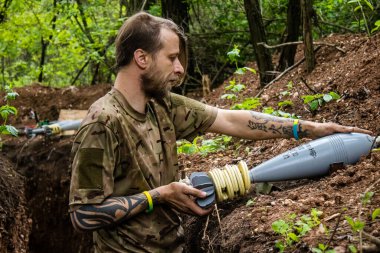 28. Topçu Taburu 'nun Ukraynalı askeri Bakhmut yakınlarındaki ormanın sıfır hattındaki bir Rus hedefine 120 mm' lik bir havan topu hazırlıyor. Rus ve Ukrayna orduları Donbass 'ta çarpışır, savaş şiddetlidir ve savaş...