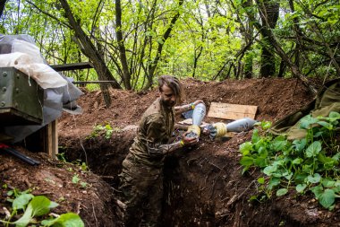 28. Topçu Taburu 'nun Ukraynalı askeri Bakhmut yakınlarındaki ormanın sıfır hattındaki bir Rus hedefine 120 mm' lik bir havan topu hazırlıyor. Rus ve Ukrayna orduları Donbass 'ta çarpışır, savaş şiddetlidir ve savaş...