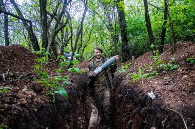 28. Topçu Taburu 'ndan Ukraynalı asker Bakhmut yakınlarındaki ormanın sıfır hattındaki Rus hedefine 120 mm' lik havan topu taşıyor. Rus ve Ukrayna orduları Donbass 'ta çarpışır, savaş şiddetlidir ve savaş...