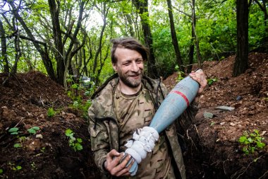 28. Topçu Taburu 'ndan Ukraynalı asker Bakhmut yakınlarındaki ormanın sıfır hattındaki Rus hedefine 120 mm' lik havan topu taşıyor. Rus ve Ukrayna orduları Donbass 'ta çarpışır, savaş şiddetlidir ve savaş...