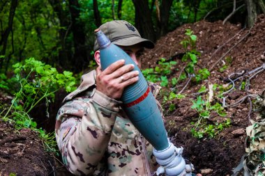 28. Topçu Taburu 'ndan Ukraynalı asker Bakhmut yakınlarındaki ormanın sıfır hattındaki Rus hedefine 120 mm' lik havan topu taşıyor. Rus ve Ukrayna orduları Donbass 'ta çarpışır, savaş şiddetlidir ve savaş...