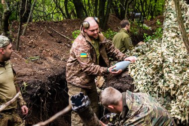 28. Topçu Taburu 'ndan Ukraynalı asker Bakhmut yakınlarındaki ormanın sıfır hattındaki Rus hedefine 120 mm' lik havan topu taşıyor. Rus ve Ukrayna orduları Donbass 'ta çarpışır, savaş şiddetlidir ve savaş...