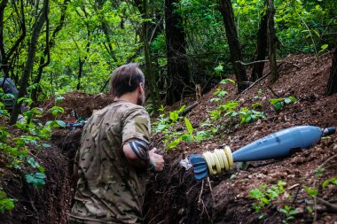 28. Topçu Taburu 'ndan Ukraynalı asker Bakhmut yakınlarındaki ormanın sıfır hattındaki Rus hedefine 120 mm' lik havan topu taşıyor. Rus ve Ukrayna orduları Donbass 'ta çarpışır, savaş şiddetlidir ve savaş...