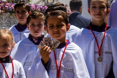 Corpus Christi geçit törenine katılan Katolik cemaatinden bir çocuk. İsa 'nın gerçek varlığını işlemek için asırlık bir Katolik inancı geleneği. Eski Carmona kasabasının dar sokaklarında dini törenler düzenleniyor.