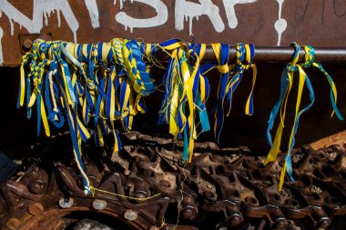 İnsanlar Ukrayna 'nın renginde bilezikler takmak için Ukrayna' nın savaşın başlangıcından beri yok ettiği Rus askeri teçhizatına geliyorlar. Bu imha edilmiş Rus askeri teçhizatının sunumu bir propaganda biçimi olarak kullanılıyor.