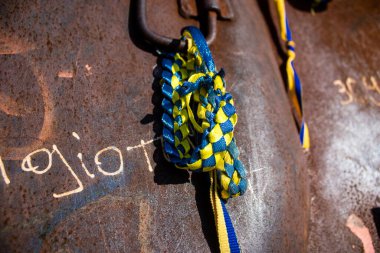 İnsanlar Ukrayna 'nın renginde bilezikler takmak için Ukrayna' nın savaşın başlangıcından beri yok ettiği Rus askeri teçhizatına geliyorlar. Bu imha edilmiş Rus askeri teçhizatının sunumu bir propaganda biçimi olarak kullanılıyor.