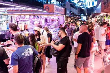 Barselona, İspanya - 28 Ağustos 2023 İspanya 'nın başkenti Barcelona' daki Boqueria gıda pazarında keyif çatan turistler.