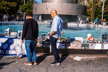 Tel Aviv, İsrail - 15 Aralık 2023. İnsanlar ibadet etmeye gelir. Dizengoff Meydanı Anıtı 'nda 7 Ekim 2023' te Hamas tarafından kaçırılan rehinelerin yüzlerinin posterleri sergileniyor..