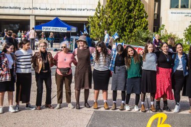 Tel Aviv, İsrail - 4 Ocak 2024 İsrailli gençler Tel Aviv 'deki Rehine Meydanı' nda hala Gazze 'de tutulan 129 rehinenin anısına şarkı söylüyorlar. İnsanlar düzenli olarak rehine ailelerini desteklemek için toplanır.