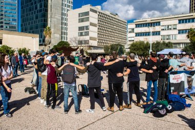 Tel Aviv, İsrail - 25 Ocak 2024 İsrailli gençler Tel Aviv 'deki Rehine Meydanı' nda hala Gazze 'de tutulan 100 rehinenin anısına şarkı söylüyorlar. İnsanlar düzenli olarak rehine ailelerini desteklemek için toplanır.