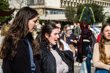 Tel Aviv, İsrail - 25 Ocak 2024 İsrailli gençler Tel Aviv 'deki Rehine Meydanı' nda hala Gazze 'de tutulan 100 rehinenin anısına şarkı söylüyorlar. İnsanlar düzenli olarak rehine ailelerini desteklemek için toplanır.